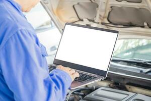 Auto mechanic working on laptop at mechanic shop, technician diagnosing car engine with a laptop with special program photo