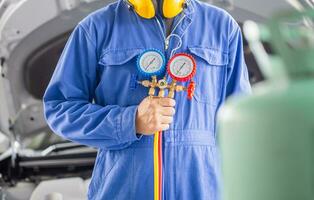 Car Air Conditioning Repair, Technician holding monitor tool to check and fixed car air conditioner system, Repairman check car air conditioning system refrigerant recharge photo
