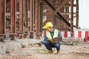 Engineer checking project at the building site, Man in hardhat with laptop at the infrastructure construction photo