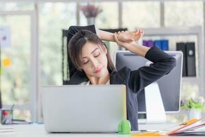 Office syndrome, Asian woman doing stretch exercise stretching her arms in work time, Female officer feeling tired and fatigue stretching to relax photo