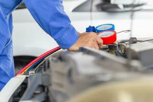 Repairman holding monitor tool to check and fixed car air conditioner system, Technician check car air conditioning system refrigerant recharge, Car Air Conditioning Repair photo