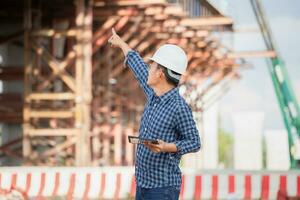 Engineer man checking project at construction site, Foreman in hardhat at the infrastructure building site photo