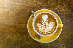 Coffee in yellow coffee cup and on a wood background photo