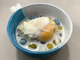 Sticky rice pearls in coconut milk with poached egg in light syrup photo