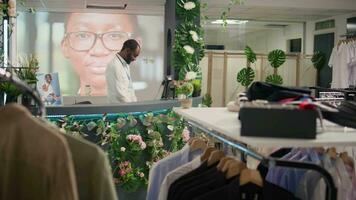 bipoc Mann Arbeiten im luxuriös Kleidung Geschäft mit elegant Sortiment von Blazer. afrikanisch amerikanisch Ladenbesitzer warten Kunden im Prämie Mode Boutique mit stilvoll Kleidung Kleider video