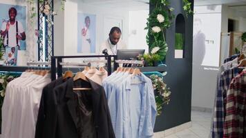 Al dettaglio assistente nel elegante moda boutique in attesa per ricevere lotto di nuovo merce, imputando dati su digitale dispositivo. lavoratore nel capi di abbigliamento memorizzare in attesa consegna di indumenti a partire dal nuovo collezione video