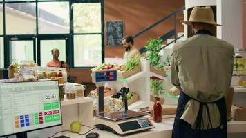 verkoper voorbereidingen treffen boodschappen bestellen voor huis levering, zetten biologisch produceren in rugzak. Afrikaanse Amerikaans werknemer komt eraan naar plukken omhoog fruit en groenten voor lokaal eco op te slaan klanten. video