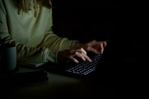 Anonymous woman working on laptop at night photo