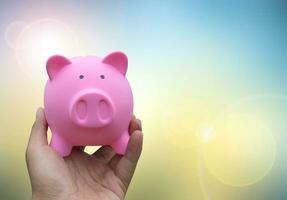 Male hand holding a pink piggy bank on blured background photo