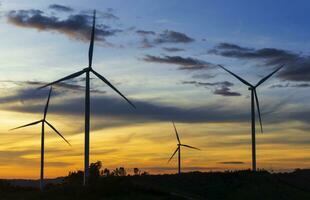 viento turbinas en puesta de sol antecedentes. natural energía foto