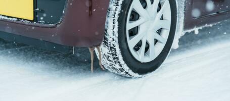 Car wheel tires on the road covered with snow in winter season, Vehicle on snowy way at snowfall photo