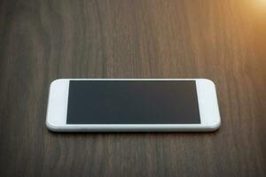 Smart phone with blank screen lying on wooden table photo