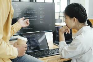 Team of young computer programmers cooperating while working on desktop PC in the office. photo