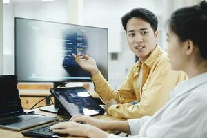 Team of young computer programmers cooperating while working on desktop PC in the office. photo