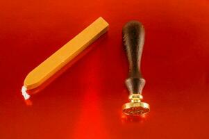 a wax stamp and a wooden stick on a red background photo