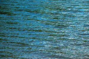 Water ripple texture background. Wavy water surface during sunset, golden light reflecting in the water. photo