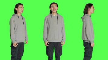 Positive man laughing on camera, posing feeling cheerful against greenscreen backdrop. Asian person smiling in studio, expressing amusing funny gestures, relaxed optimistic guy. video