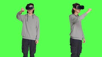 Male person using virtual reality gadget in studio with greenscreen backdrop, having fun with interactive 3d headset. Modern asian man enjoying artificial intelligence vr glasses. video