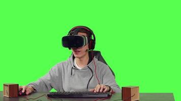 POV of guy set up at desk over greenscreen backdrop, enjoying virtual reality online games with friends. Young person gaming with vr headset, playing action or adventure gameplay. video