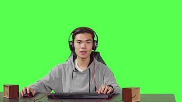 POV of man enjoying video games at pc while he talks to his friends on headphones, playing computer action game at his workstation desk. Young gamer having fun with gameplay.