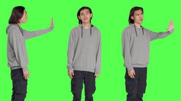 Model showing stop sign with palm in studio with greenscreen background, advertising refusal and rejection on camera. Unhappy displeased person doing no symbol, disagreeing with something. video