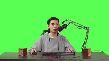 POV of video blogger on live stream recording game of new adventure videogames launched, full body greenscreen backdrop. Asian streamer broadcasting rpg web competition, streaming with microphone.