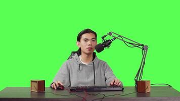 POV of vlogger broadcasting rpg gameplay over full body greenscreen in studio, content creator streaming live web contest. Asian video blogger playing games and broadcasting at desk.