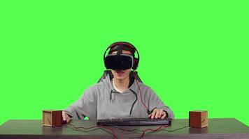 POV of player enjoying vr video games sitting at his desk over greenscreen backdrop, playing web based with friends and having fun with rpg gameplay. Man using virtual reality headgear.