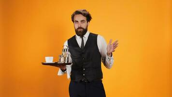 Shocked waiter with surprised reaction carrying coffee and cutlery of meal tray, being in shock on camera. Skilled elegant butler givign assistance to clients, experiencing surprise. photo