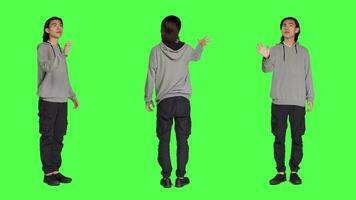 Male model looks at hologram icon on camera with full body greenscreen backdrop, examining modern holographic image and focusing on his work. Asian relaxed person using artificial intelligence. video