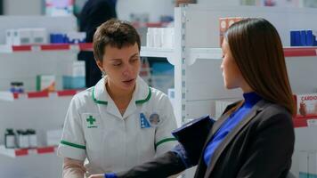 experto farmacéutico en boticario utilizando sangre presión monitor dispositivo en asiático paciente, mirando para auricular fibrilación y otro médico cuestiones durante rutina examen foto