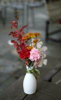 flowers in white vase on wooden table photo