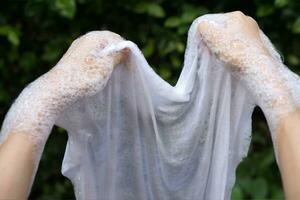 mano Lavado y eliminar manchas en blanco ropa. foto