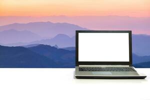 Laptop on white desk with natural scene multicolor mountain layer photo