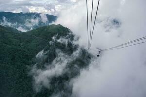 Cable car carries passenger moving over the mountain among the foggy in cloudy day photo