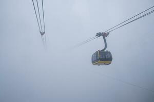 cable coche lleva pasajero Moviente en el montaña entre el brumoso en nublado día a sapa foto
