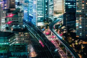Several sky train passing through illuminated building in business district at Tokyo, Japan photo