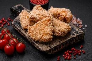 Delicious fresh crispy chicken nuggets on a dark concrete background photo