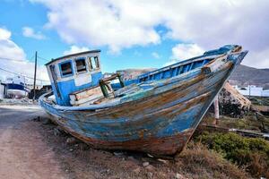 an old boat sits on the side of the road photo