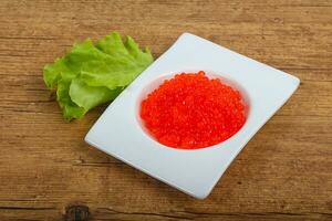 Red caviar over wooden background photo