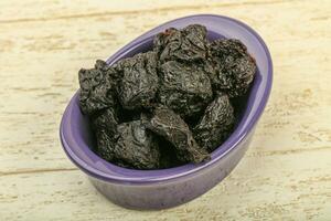 Dried plums over wooden background photo