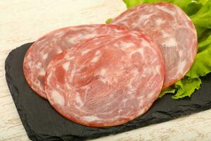 Sliced sausage over wooden background photo