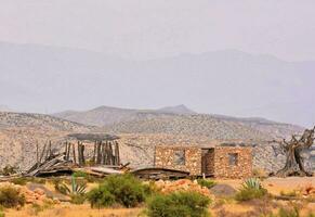 an old house in the desert with mountains in the background photo