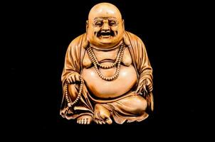 a statue of a laughing buddha sitting on a black background photo