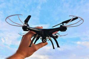 a person holding a remote control drone in front of a blue sky photo