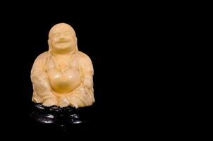 un estatua de un riendo Buda sentado en un negro antecedentes foto