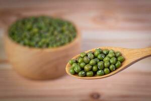 Green beans in a wooden spoon with Green beans in a wooden cup placed on a wood panel. photo