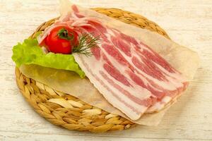 Raw bacon over wooden background photo