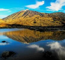 a mountain is reflected in a small lake photo