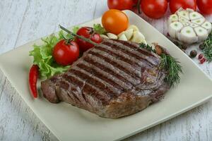 Ribeye steak over wooden background photo